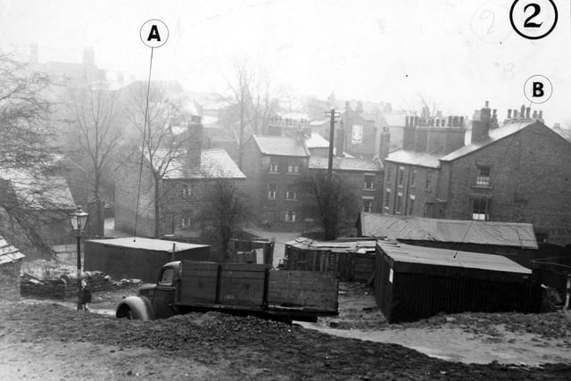 Burley village, with garages and outhouses in the foreground in January 1950. A lorry is parked near one of the garages and a small child is standing next to a lamp post.
