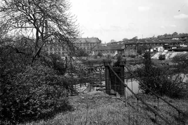 April 1954 and pictured is Burley Mills iron suspension bridge built by Benjamin Gott in the early 19th century. Burley Mills is in the background.