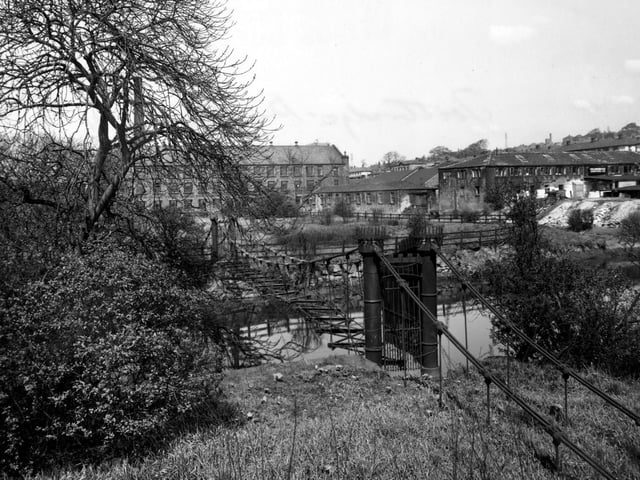 April 1954 and pictured is Burley Mills iron suspension bridge built by Benjamin Gott in the early 19th century. Burley Mills is in the background.