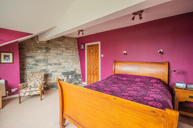 A quirky bedroom with an exposed stone wall within the cottage.