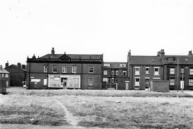 A view across to Hardy Street from the former Stewart Place in August 1983. The two areas of grass were once the site of red brick streets Ellis Place and Stewart Place, foreground. The building with shop frontage is the former Co-op.
