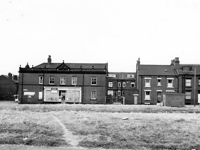 A view across to Hardy Street from the former Stewart Place in August 1983. The two areas of grass were once the site of red brick streets Ellis Place and Stewart Place, foreground. The building with shop frontage is the former Co-op.