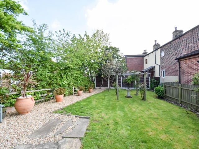 A pebbled area with seating, and a stretch of lawn within the gardens.