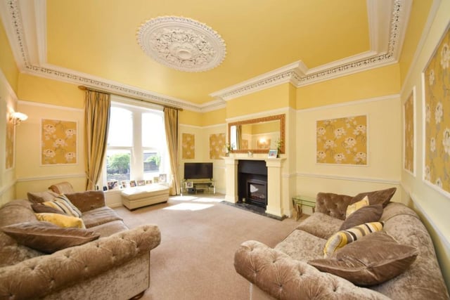 This sunny room benefits from a large window, with a central feature fireplace, and detailed decor.