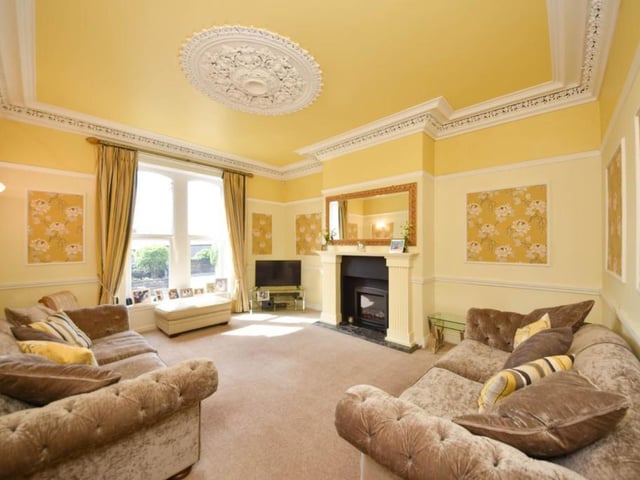 This sunny room benefits from a large window, with a central feature fireplace, and detailed decor.