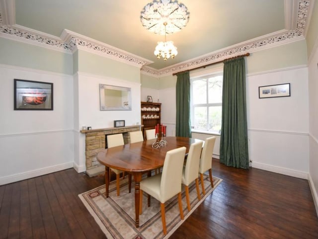 This room, with wooden floor and stone fireplace, has room for a large dining table and chairs.