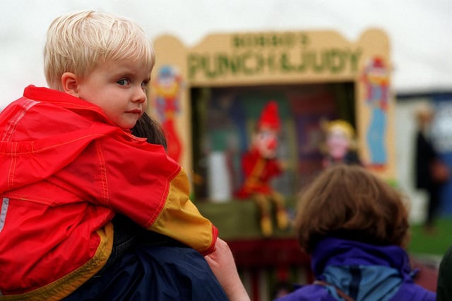 Scott Elliott Simmons sits on his dad's shoulder as they both watch a Punch and Judy Show at Otley Show in 1997.