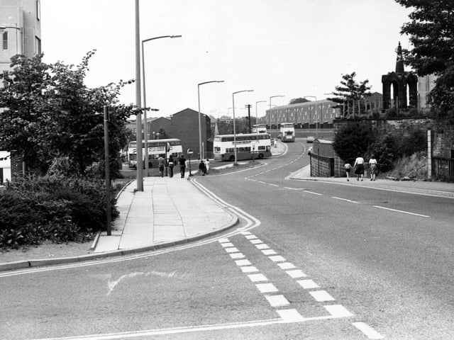 Lower Town Street, with the entrance road to Bramley Shopping Centre in the foreground. On the right the church spire of the old St.Margaret's church can be seen behind a high wall.