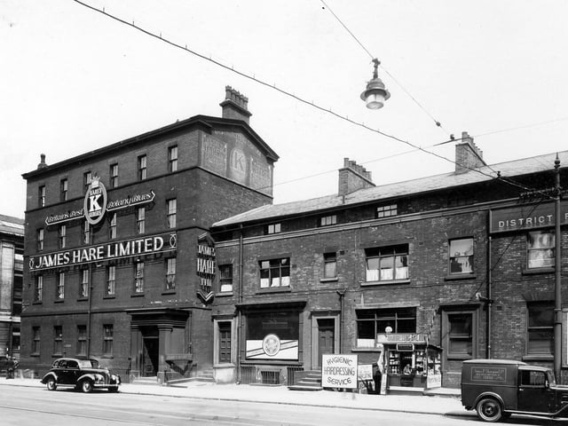 The James Hare woollen warehouse on Wellington Street in June 1939. The cellar of number 68 has a sign for Hygenic Hairdressing Saloon and next to this a cigarette kiosk with a bored looking lady.