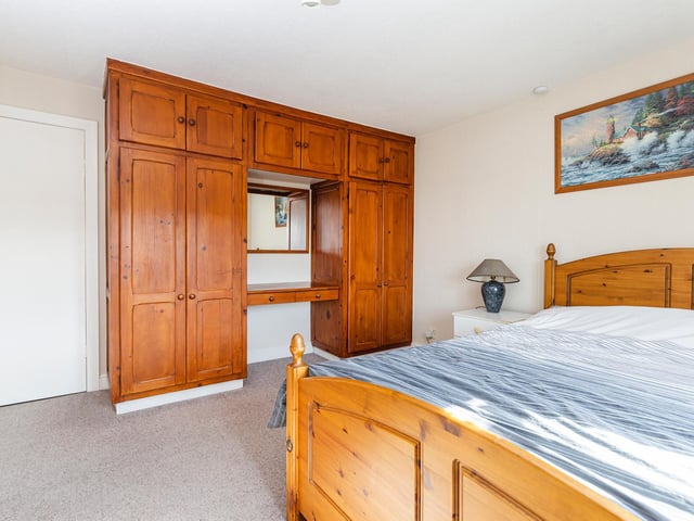 This double bedroom includes fitted wardrobes and cupboard units.