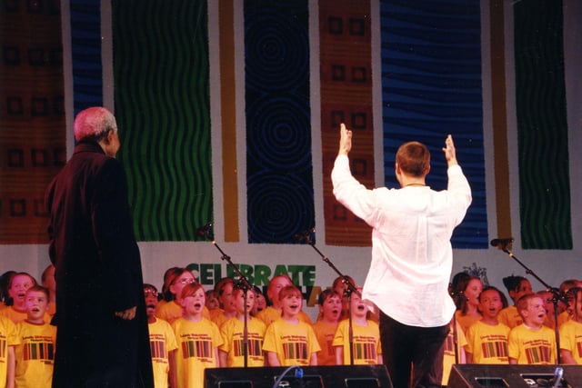 A choir of 99 children from schools around the city centre sing the South African National Anthem for Nelson Mandela, pictured left, in April 2001. They are wearing bright yellow tee shirts with the words "Leeds Welcomes Nelson Mandela" on the front and the colours of the South African flag.