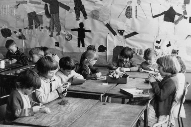 A group of children taking part in crafts activities, including knitting, sewing, and jigsaws. On the back wall is a collage showing a variety of figures.