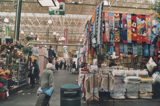 Aisle G inside Kirkgate Market - plant and flower shop to left pictured in September 1999. Shop to the right selling textiles including towels, bed sheets, pillows and cushions.