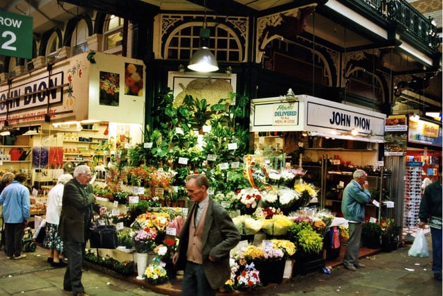 John Dion's flower and plant stall. A wide selection of fresh cut flowers and house plants are available. To the left the stall also sells gardening equipment including watering cans and bulbs.