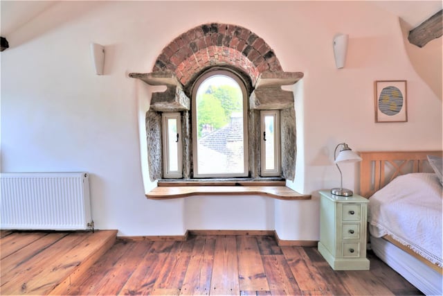 A deeply set stone and brick arched window in the 'attic' room with wide sill.
