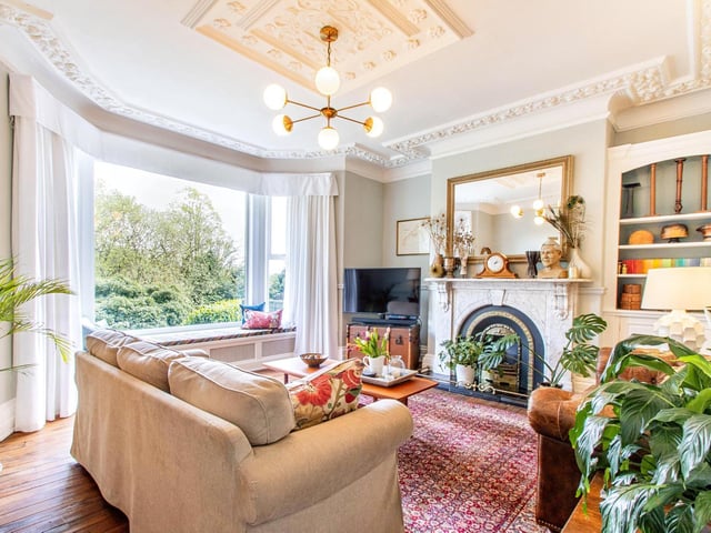A huge window with a garden scape in this lounge with marble fireplace and inbuilt book shelves.