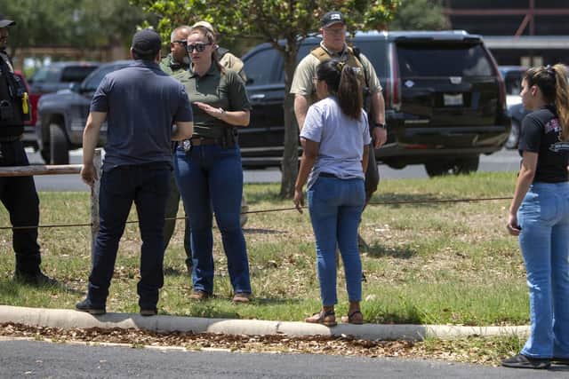A law enforcement officer speaks with people outside Uvalde High School after shooting a was reported earlier in the day at Robb Elementary School, Tuesday, May 24, 2022, in Uvalde, Texas. (William Luther/The San Antonio Express-News via AP)