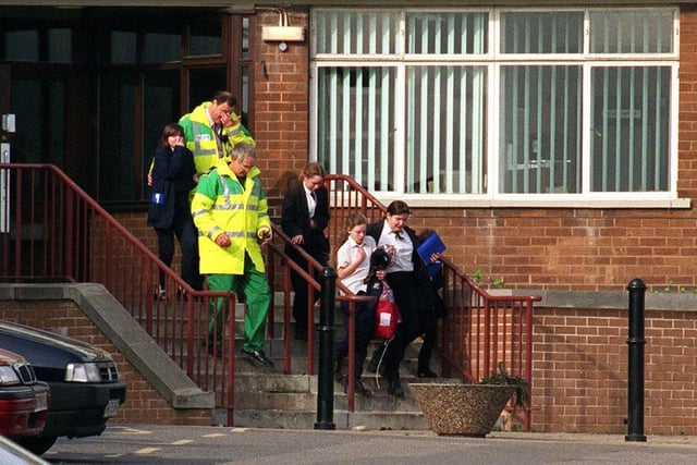 Pupils from West Leeds High School are led away by ambulance men after the roof of their school was blown off in high winds in February 1998.