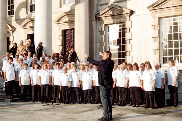 A performance by the Sing Live Northern choir outside Leeds Civic Hall in November 2003.. The choir performed as part of a ceremony celebrating the 30th Anniversary of the Ark Royal receiving the Freedom of the City of Leeds. In the foreground is John Morris, conductor and founder of Sing Live.