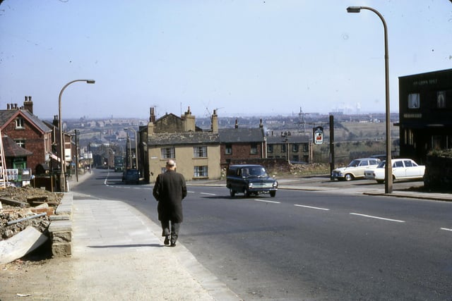 A view looking down Churwell Hill in April 1968 from just above the Old Golden Fleece pub. It was a Tetley's pub at this time and is shown on the right with two cars in its car park. This photo was taken just after the shops had been demolished. The old millinery shop once run by Mrs. Wilson is still standing but no longer in use for that purpose.