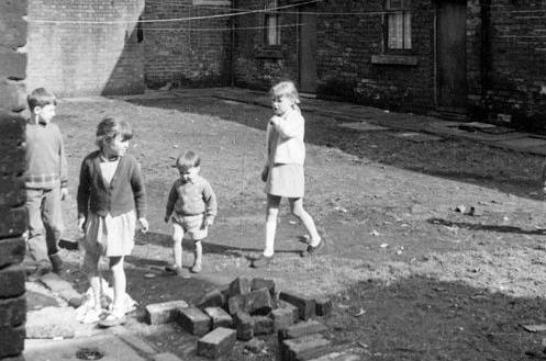 Terraced houseson Back Barker Square in April 1969. Children are playing on the unmade road and a pile of bricks and rubble are in the foreground.