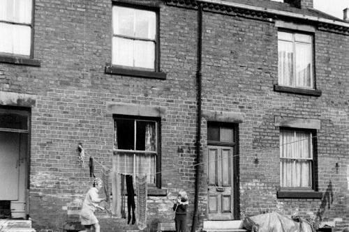 A woman is hanging and washing and two children are playing on the unmade road. Stables Yard was located behind Commercial Street.