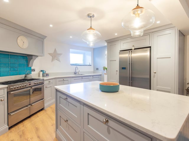 A modern kitchen with quartz worktops and a central island,