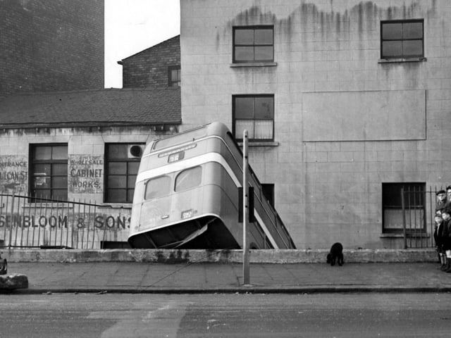 An alternative view of the bus crash in January 1956 with people watching including schoolboys in short trousers.
