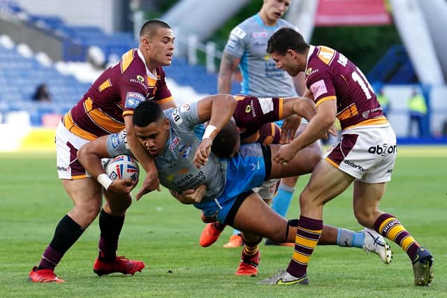 Leeds Rhinos' David Fusitu'a is tackled by Huddersfield Giants' Tui Lolohea (left), Josh Jones and Jack Cogger (right) at the John Smith's Stadium Picture: Martin Rickett/PA
