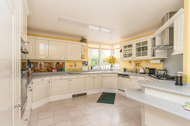 A kitchen with fitted units and Corian worktops, includes a six-ring gas hob, an electric double oven and an integrated fridge. There's also a separate utility room.