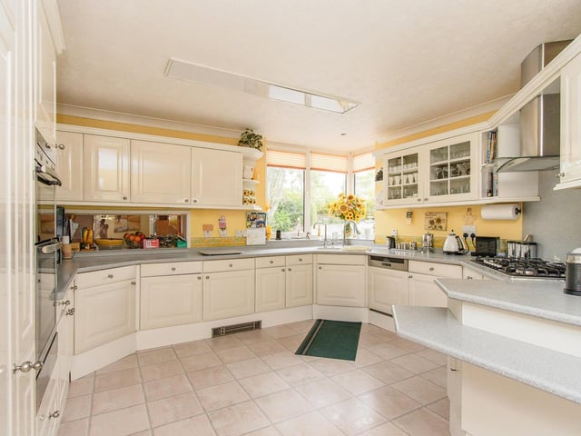 A kitchen with fitted units and Corian worktops, includes a six-ring gas hob, an electric double oven and an integrated fridge. There's also a separate utility room.