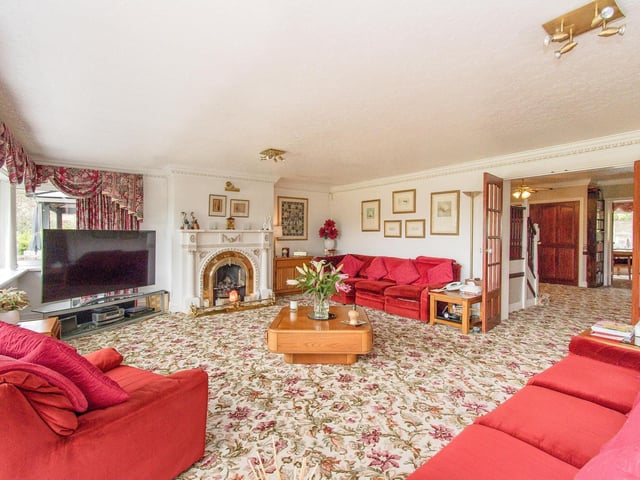 A large, open lounge with windows lining one wall and a feature fireplace.