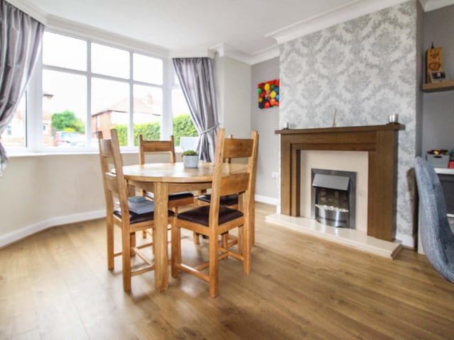 The dining room has ample space for a large table, with a fireplace and large windows to allow plenty of natural light.
