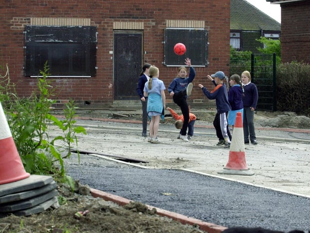 Youngsters play football amongst the debris left by Leeds City Council during work to properties on Grayrigg Close in Halton Moor.