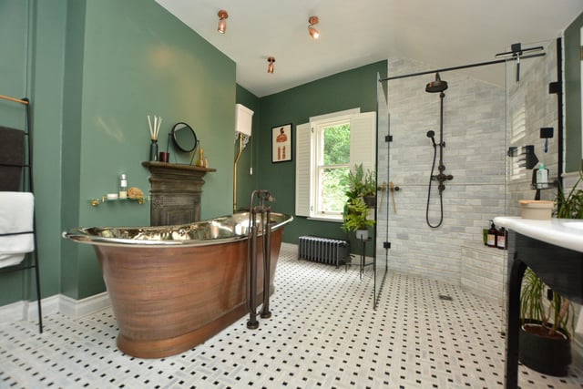 a stunning house bathroom features a fired earth free standing copper bath and a large walk-in shower.