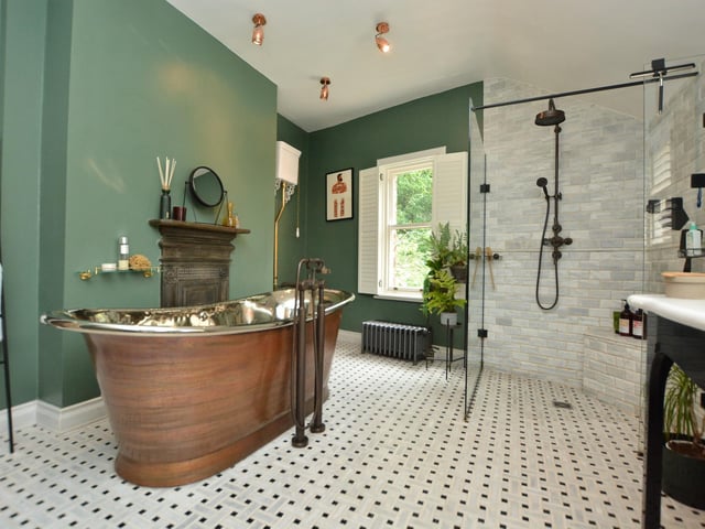 a stunning house bathroom features a fired earth free standing copper bath and a large walk-in shower.