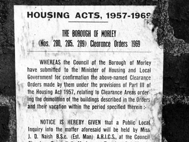 A notice on the wall of a house on Parker Street in East Ardsley in December 1970. It advertises a public inquiry into the demolition of the buildings to be held in the Council Chamber at Morley Town Hall.