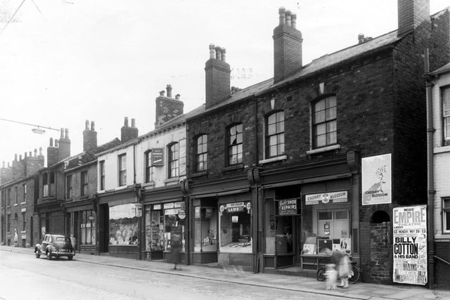 A parade of shops on Beckett Street in May 1960. Thye include hairdressers, then Beckett Street post office, a  butchers shop and a shoe repair business. The edge of Peel Public House is on the right edge.