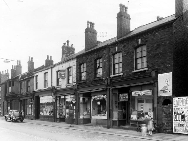 A parade of shops on Beckett Street in May 1960. Thye include hairdressers, then Beckett Street post office, a  butchers shop and a shoe repair business. The edge of Peel Public House is on the right edge.