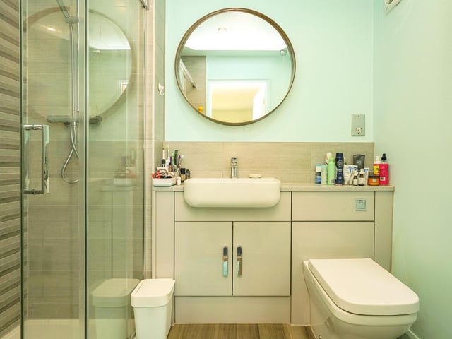 The elegant en-suite is fitted with a walk-in shower cubicle with a sliding shower screen, a combination vanity unit with a wash hand basin and a toilet.