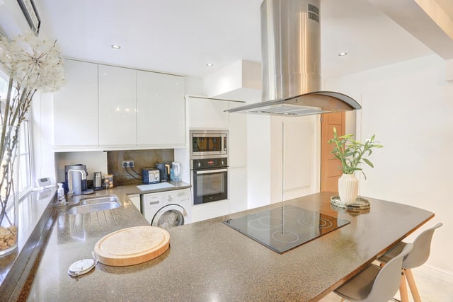 The kitchen is fitted with a range of modern white high gloss wall and base units, with complimentary work surfaces over the stainless steel sink and draining area.