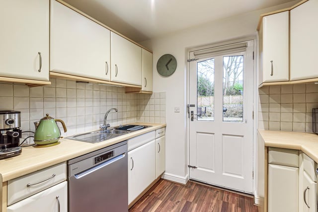 The kitchen is spacious with beautiful wooden floors and cream cabinets.