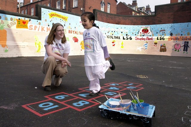 Leeds Metropolitan University student Kate Miskin takes time out to watch Roheela Parveen play hop scotch after helping to paint a mural in the school playground in March 2003.