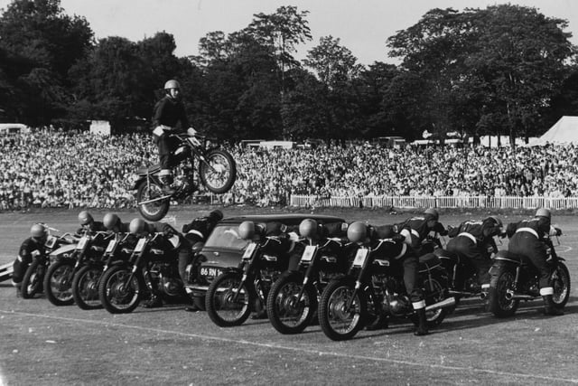 A member of the Rotal Marines Motor-cycle Display Team performs a spectacular leap over 14 men and a mini car at Leeds Gala at Roundhay Park in August 1972.