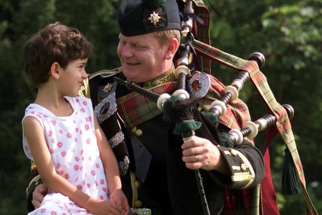Piper Major Ian Hutton of the Royal Dragoon Guards gives a holding hand to Kosovan refugee Gentiana Mustafa in July 1999.