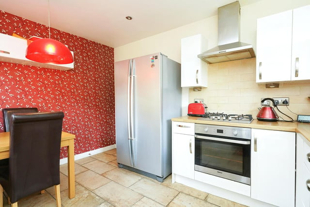A modern kitchen with a range of wall and base units and integrated appliances is tucked away around the corner, with a small dining space also included.
