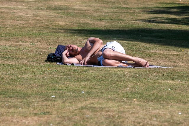 A man a sleeps in the midday sun at Roundhay Park earlier today.