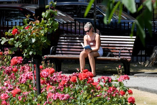 Pictured is a woman reading a book in Park Square in the city centre earlier this morning.