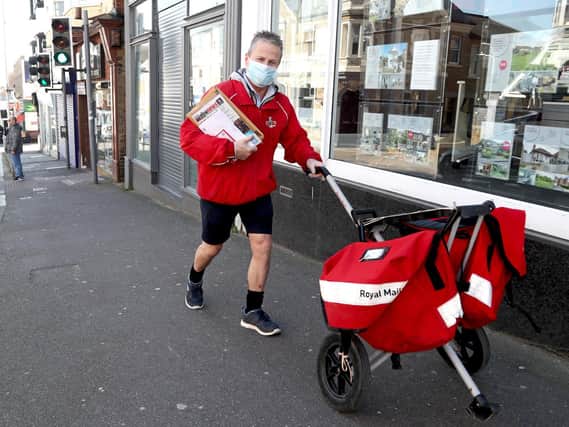 File photo of a postman wearing a mask and gloves to deliver letters in Broadstairs, Kent.