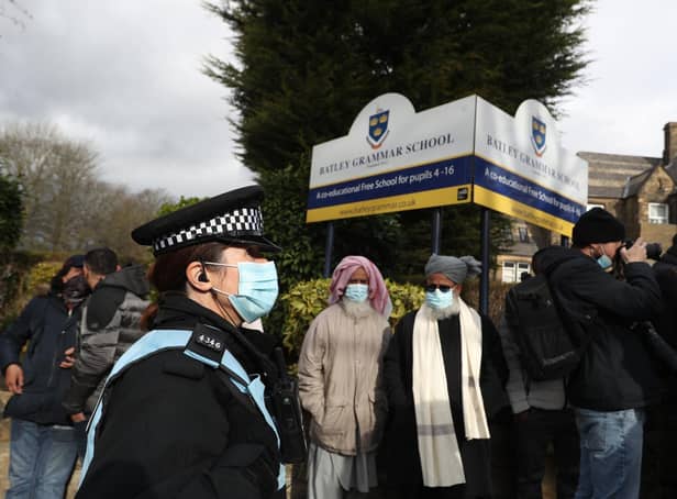 A police officer observes protesters gathered outside Batley Grammar School in Batley, West Yorkshire, where a teacher was suspended for reportedly showing a caricature of the Prophet Mohammed to pupils during a religious studies lesson in March. Photo credit:  Danny Lawson/PA Wire
